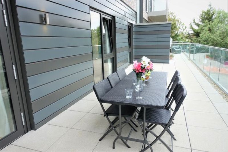 Modern patio with black dining table, four chairs, and pink flowers in vase