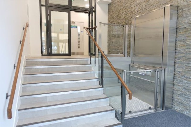 Interior staircase with metal railings, glass partition, and brick wall detailing