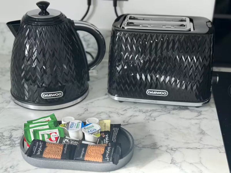 Kitchen counter with black kettle, toaster, and tray of packaged food items