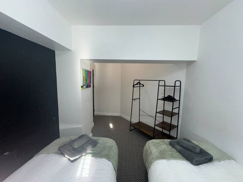 Small bedroom with two single beds, metal shelving unit, and minimalist décor