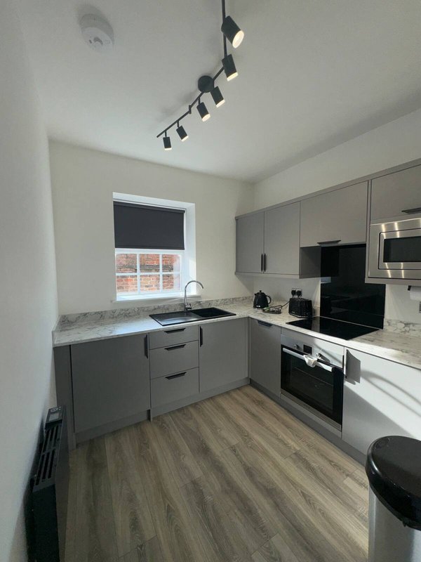 Modern kitchen with gray cabinetry, black appliances, granite countertop and window