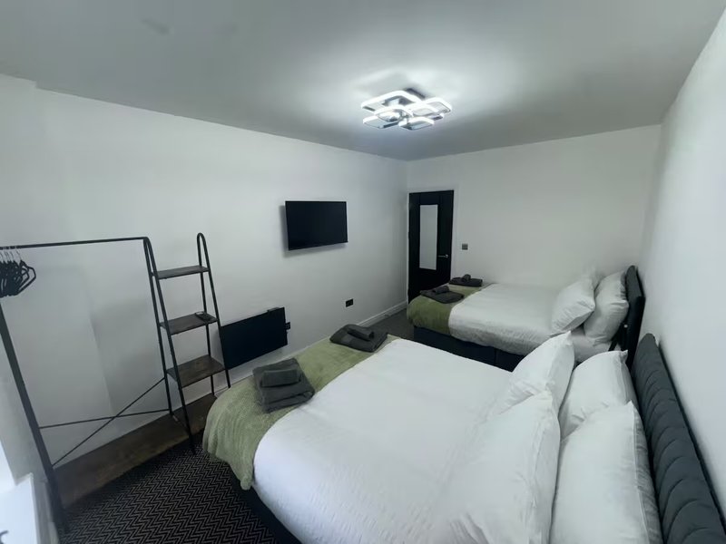 Bedroom with two single beds, wall-mounted TV, ladder shelf and modern ceiling light