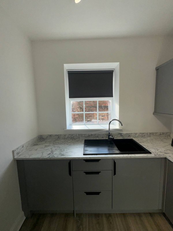 Modern kitchen with dark cabinetry, granite countertop, black sink and window with blinds