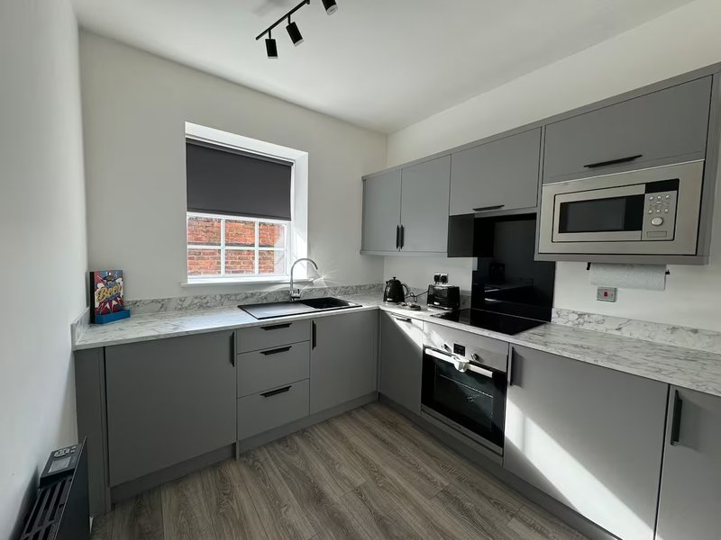 Modern kitchen with grey cabinetry, marble worktops, stainless steel appliances and window
