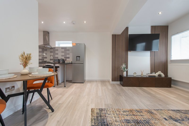 Modern open-plan kitchen and living area with stainless steel appliances and wooden flooring