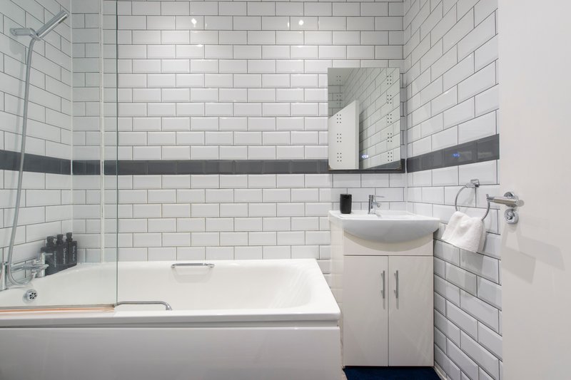 Modern bathroom with white subway tile, bathtub, pedestal sink and mirror cabinet