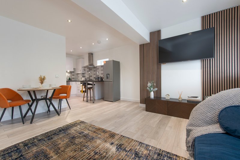 Open-plan living space with dining area, kitchen, and lounge with TV wall