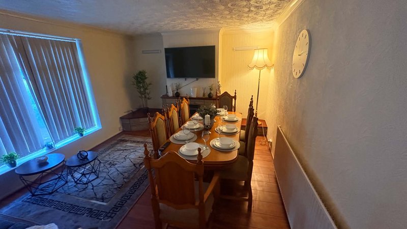 Dining room with wooden table, place settings, chairs and wall-mounted TV