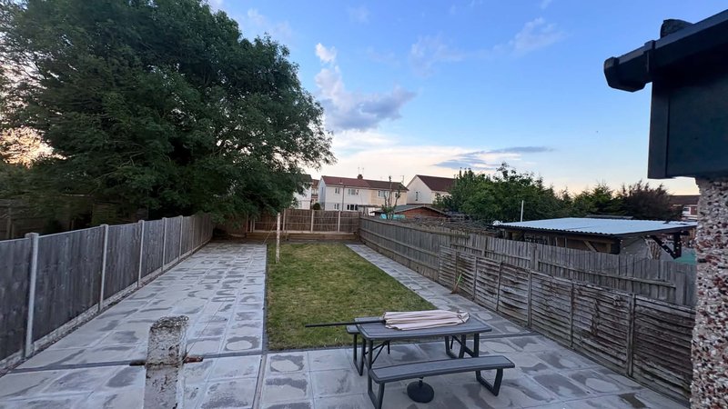 Paved garden area with picnic table, wooden fencing, lawn and neighboring houses visible