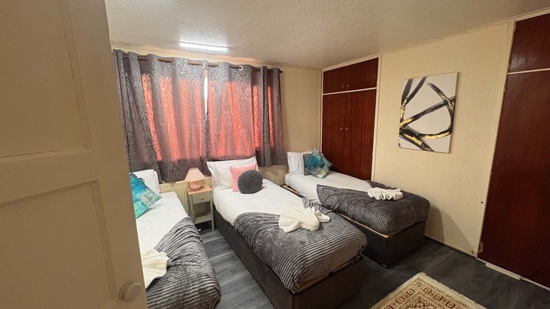 Twin bedroom with two single beds, curtained window, wardrobe and wall art