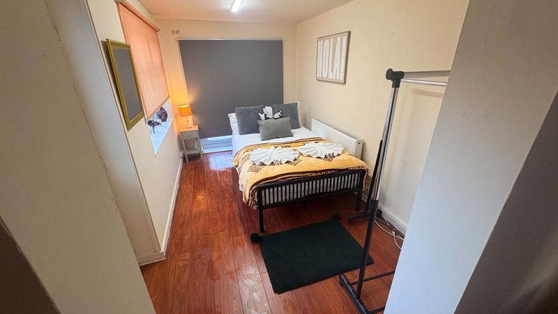 Bedroom with double bed, wooden floor, dark accent wall and bedside furniture