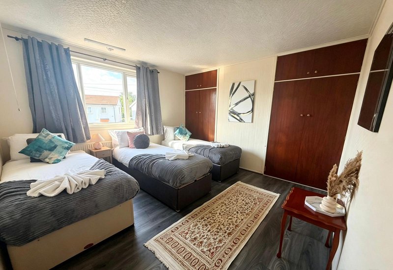 Bedroom with two single beds, blue curtains, wooden wardrobes and small table
