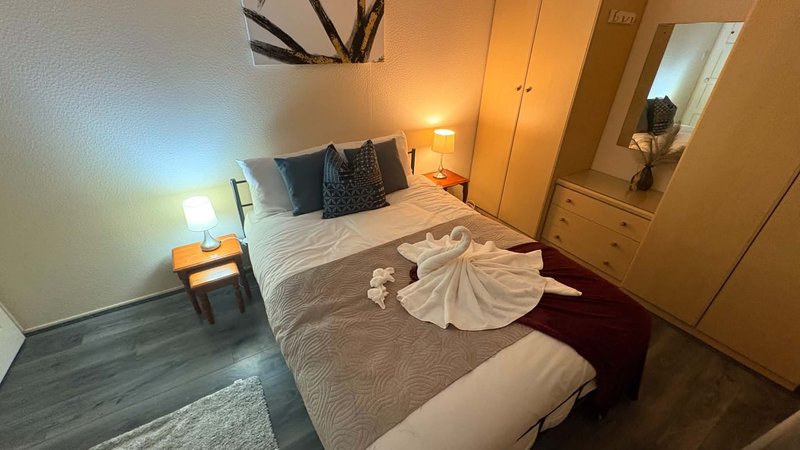 Bedroom with double bed, bedside lamps, wooden wardrobe and mirror