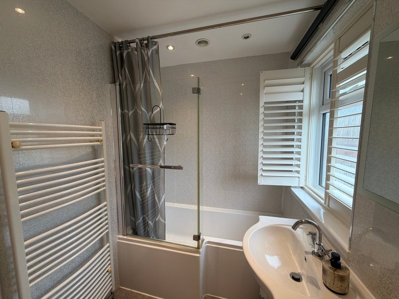 Modern bathroom with walk-in shower, heated towel rail, sink and window with shutters