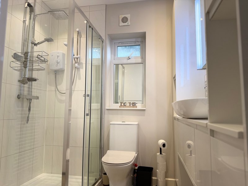 Modern bathroom with shower cubicle, toilet, sink and window