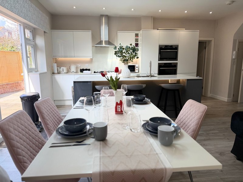 Modern open-plan kitchen and dining area with white cabinetry, island, and marble dining table