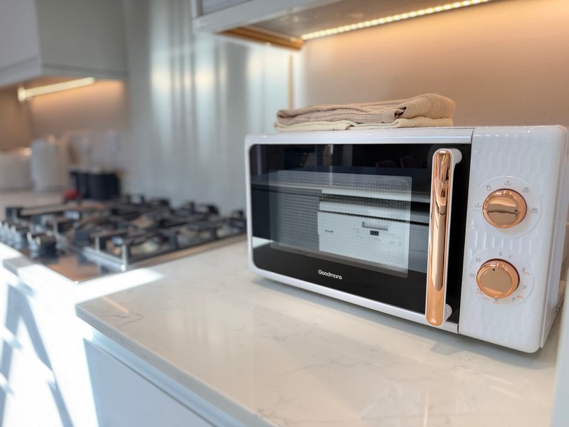 Modern white kitchen with microwave oven, gas stovetop, and wooden accents