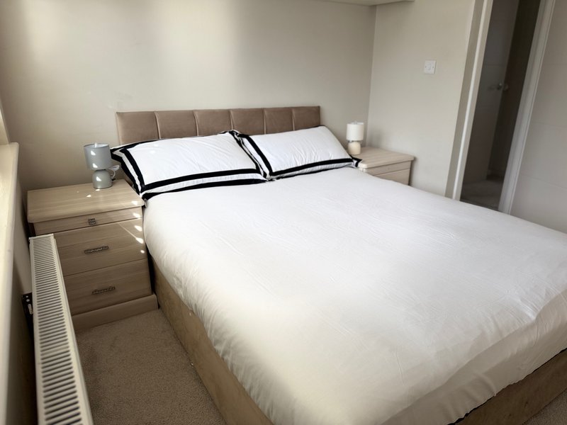 Modern bedroom with double bed, upholstered headboard, bedside tables and white bedding