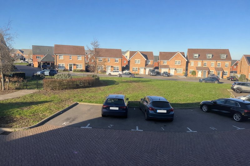 Brick townhouses with parking area, multiple vehicles, and green space