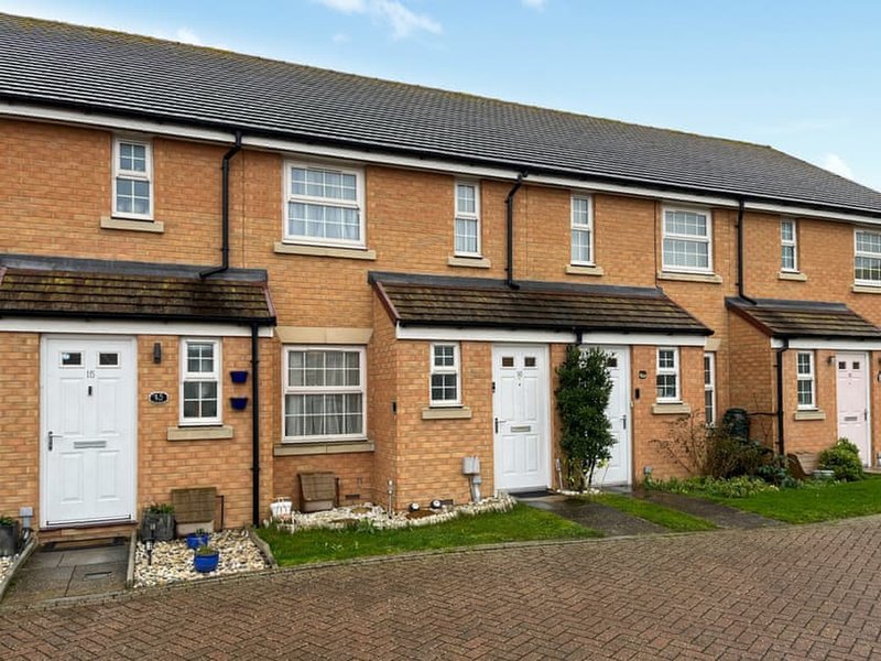 Row of brick terraced houses with white doors, small front gardens and driveway