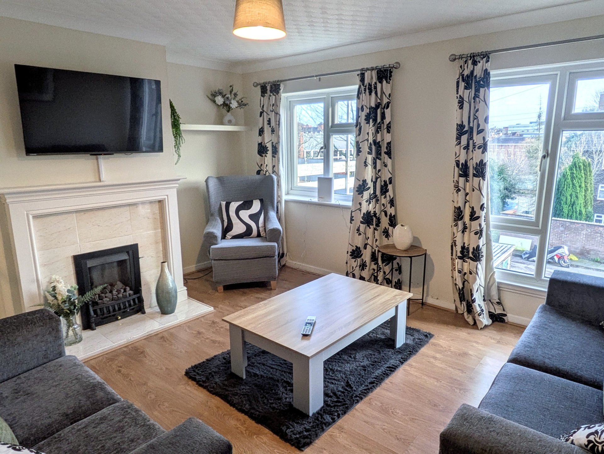 Spacious and comfortable living room with two sofas, an armchair, Smart TV and a feature fireplace. A welcoming communal space where groups can relax, watch TV and unwind together after a busy day.