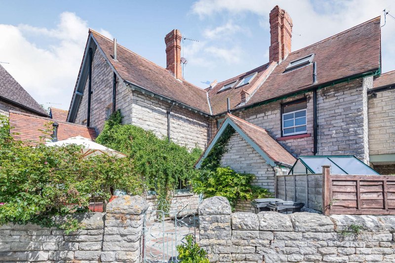 Traditional stone and brick house exterior with multiple chimneys, ivy-covered wall and wooden garage doors