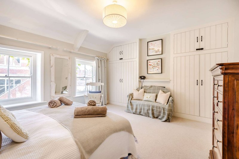 Bright bedroom with two beds, built-in wardrobes, framed artwork and wooden furniture