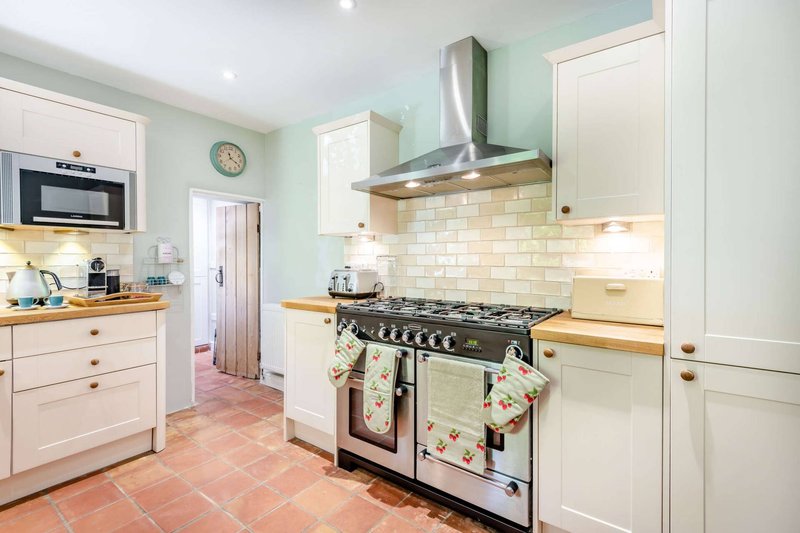 Modern kitchen with cream cabinets, subway tile backsplash, black range cooker and stainless steel hood