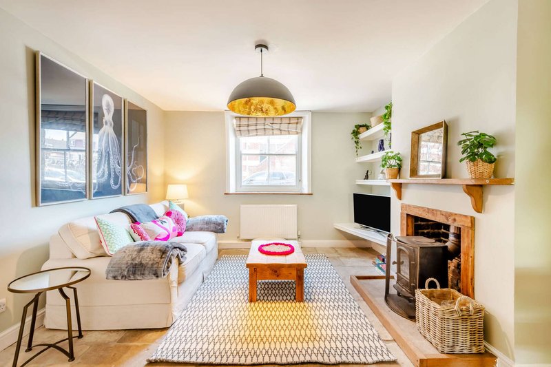 Bright living room with cream sofa, fireplace, wooden shelving, pendant lamp and large window