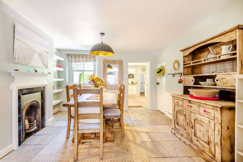 Open-plan kitchen-diner with wooden table, fireplace, pendant lighting and built-in storage
