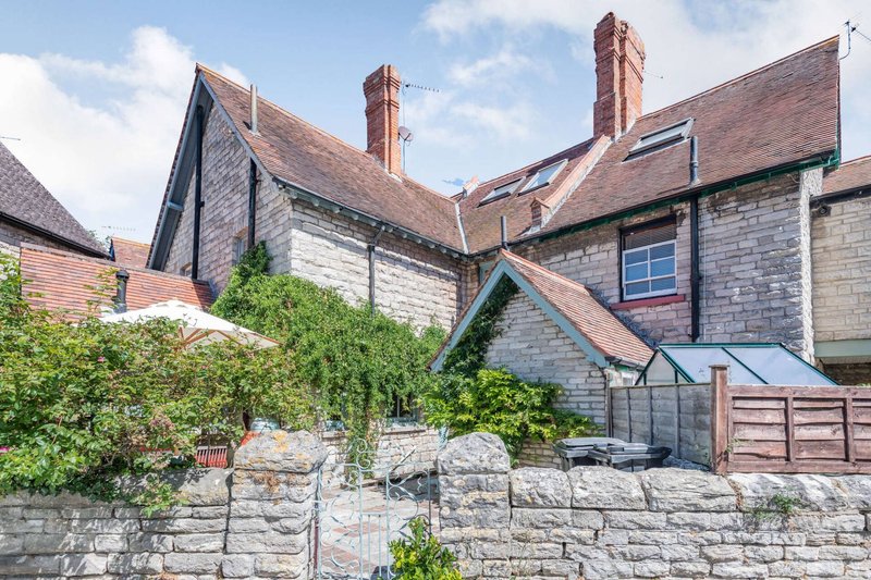 Traditional stone and brick house with ivy-covered wall, chimneys, and slate roof