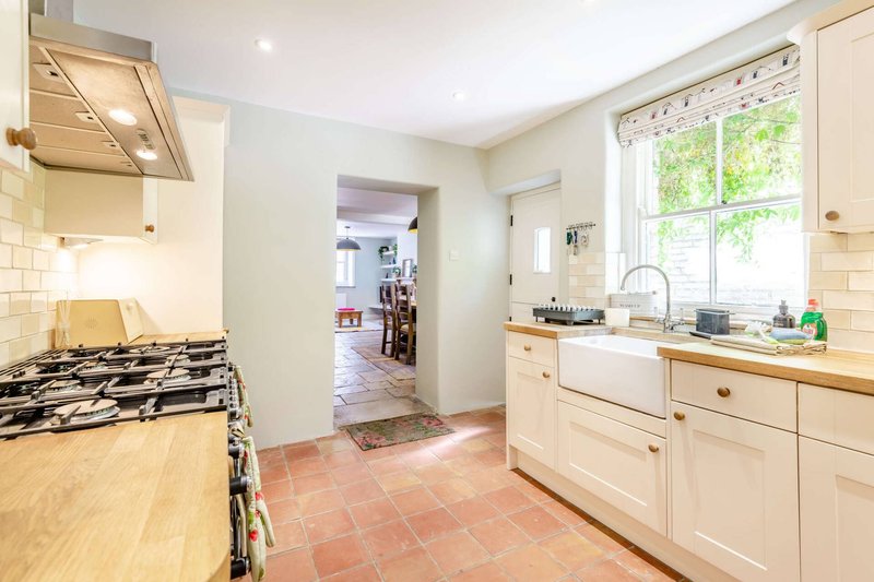 Bright kitchen with cream cabinetry, wooden countertop, gas hob and farmhouse sink