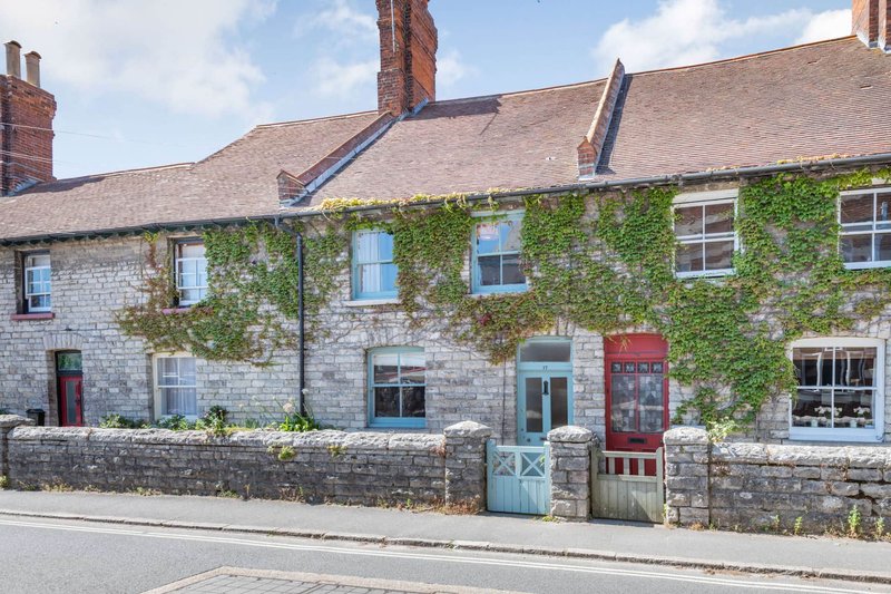 Stone terraced cottages with ivy-covered walls, blue doors and windows, street frontage