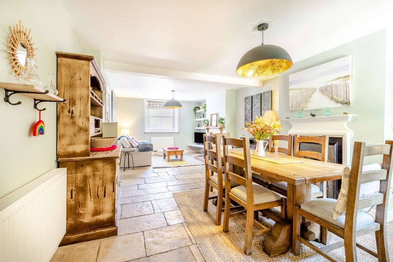 Open-plan kitchen and dining area with wooden table, pendant lights, and cream walls