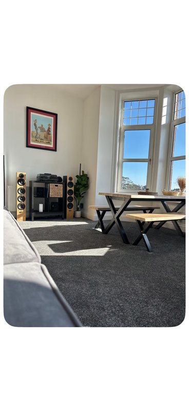 Bright living room with large windows, dining table, fireplace, and framed wall art