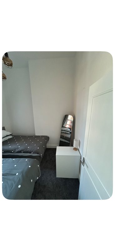 Small bedroom with single bed, white walls, dark carpet and storage furniture