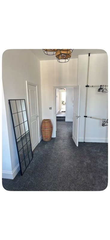 Hallway with white walls, dark carpet, doors and decorative pendant light fixture