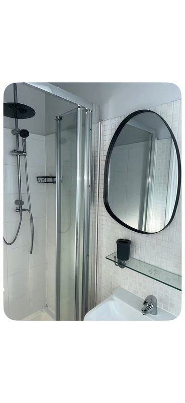 Modern bathroom with walk-in shower enclosure, oval mirror and white tile walls