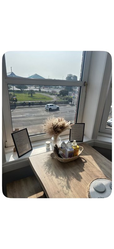Modern interior with wooden table, decorative vase, and large windows overlooking parking area and countryside