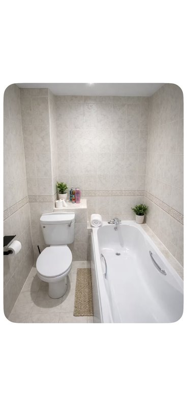 Small bathroom with toilet, bathtub, sink, and potted plants on shelves