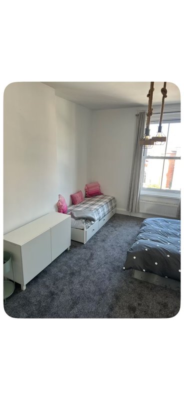Bedroom with single bed, white storage unit, window and dark grey carpet