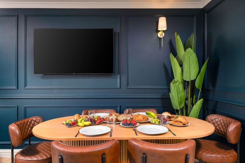 Dining room with round table, leather chairs, place settings, and wall-mounted TV