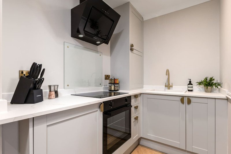 Modern kitchen with white cabinetry, black appliances, and wooden flooring