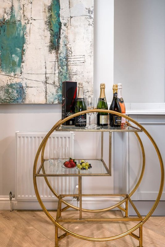 Gold circular bar cart with champagne bottles, glasses, and decorative fruit display