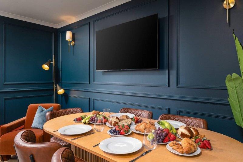 Dining room with wooden table, orange chairs, blue paneled walls and wall-mounted TV
