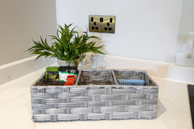 Bathroom counter with woven storage basket, potted plant, and wall-mounted outlets