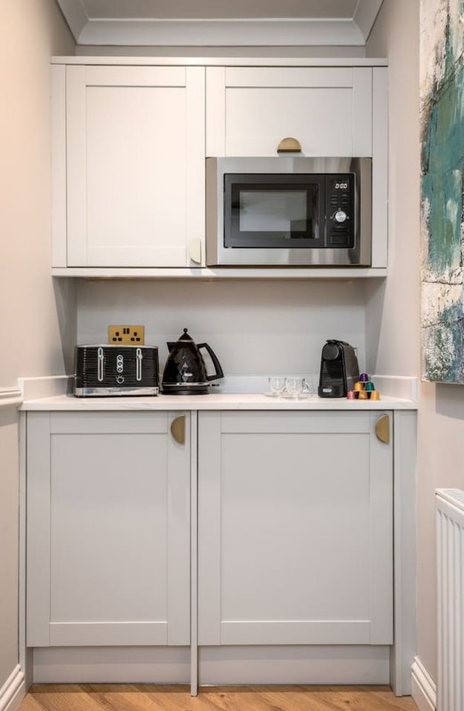Modern kitchen nook with white cabinetry, built-in microwave, and countertop appliances