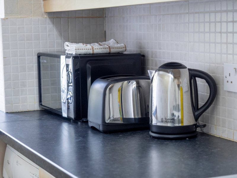 Kitchen counter with kettle, toaster, and small appliances on dark worktop