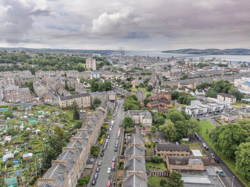 Aerial view of urban neighborhood with residential buildings, streets, green spaces and distant cityscape