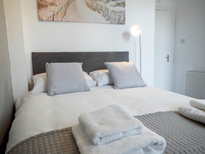 Modern bedroom with double bed, gray headboard, white bedding, and floor lamp